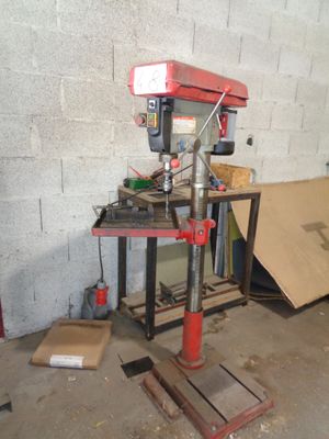 a drill press in a garage with a lot of tools