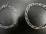 two silver bracelets on a table with a black background