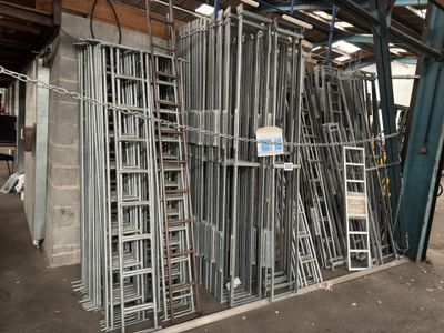 a large pile of metal ladders in a warehouse