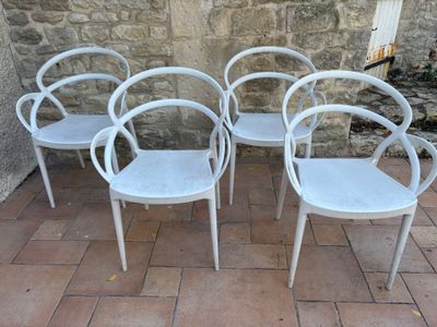 quatre chaises blanches alignées les unes à côté des autres sur un sol en briques