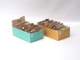 two boxes of brown and green tea bags on a white surface