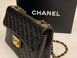 a black chanel bag with a gold chain and a black box