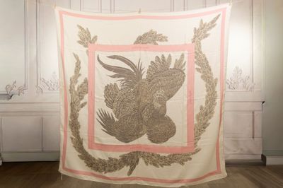 a quilt with a bird on it hanging on a wall