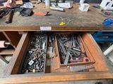 a man that is sitting at a table with a drawer full of tools