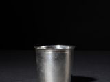 a close up of a metal cup on a table with a black background