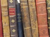 many old books lined up on a shelf in a row