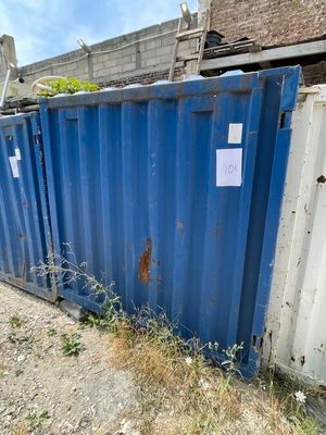 un conteneur bleu posé par terre à côté d'un bâtiment