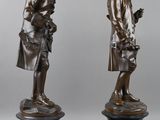 two bronze statues of a man and a woman standing on a pedestal