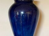 a blue vase sitting on a shelf next to a lamp