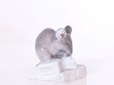une figurine représentant une souris assise sur un morceau de glace
