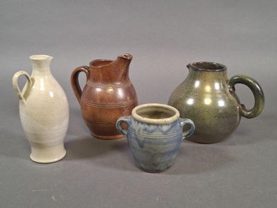 quatre vases de couleurs différentes posés les uns à côté des autres sur une surface grise