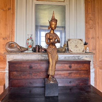 une statue représentant une personne assise sur une table en bois