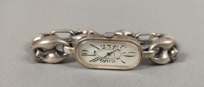 un bracelet en argent orné d'une montre, posé sur une table