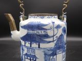 blue and white teapot with handle on a black surface