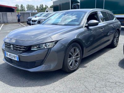 La voiture grise est garée sur le parking, à côté d'autres voitures.