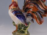 une figurine représentant un coq sur un socle vert