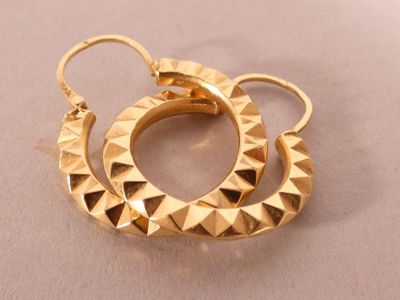 an image of a pair of gold earrings on a white surface