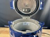 an image of a blue and silver electric cooker sitting on a wooden table