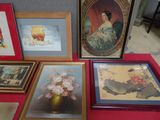 many framed pictures on a red table with a vase of flowers