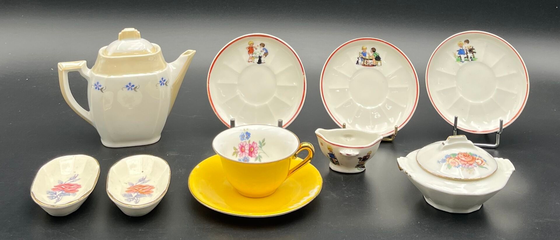 Ensemble de neuf pièces de poupée dont : - deux raviers en porcelaine à fond blanc et décor floral polychrome. - une ...