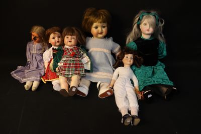 five dolls sitting next to each other on a black surface