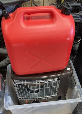 un bidon d'essence rouge posé sur un récipient en plastique