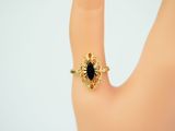 an image of a woman ' s hand with a gold ring with a black stone