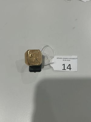 une bague en or posée sur une table blanche, avec une étiquette de prix