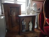 trois statues de Jésus et de Marie posées sur une table à côté d'une chaise rouge