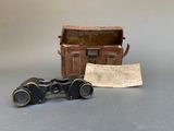 une vieille paire de jumelles posée à côté d'un sac et d'un bout de papier