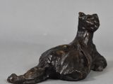 bronze statue of a cat laying down on a gray surface