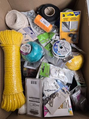 une boîte en carton remplie de divers objets, notamment de la laine, des ciseaux, des ciseaux et d'autres objets