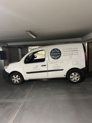 une camionnette blanche garée dans un garage, avec une pancarte sur le côté du véhicule