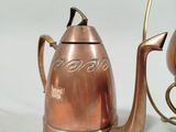 a copper teapot and a teapot on a table