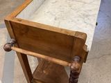 an old wooden table with a marble top in a room