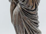 statue of a woman in a draped dress with her hands on her hips