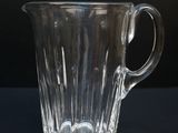 a glass pitcher sitting on a table with a black background