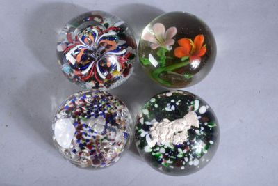 quatre billes de verre aux motifs variés, posées sur une table