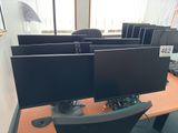 four computer monitors sitting on a desk in an office