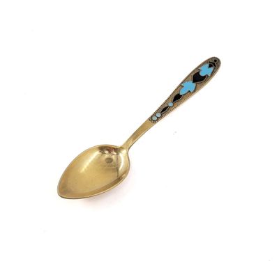 a spoon with a blue flower on it on a white surface