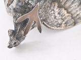 a silver figurine of a bird on a white surface