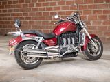 a red motorcycle that is parked in front of a brick wall