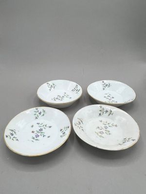 four white plates with floral designs on them on a gray surface