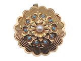 une photo en gros plan d'une broche ornée d'une perle