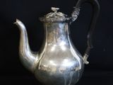 an antique silver tea pot with a handle on a black background