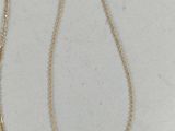 two gold necklaces on a white surface with a gold chain