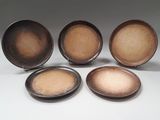 quatre assiettes marron posées les unes à côté des autres sur une surface blanche