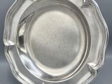 a silver plate on a stand on a grey background
