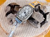 a silver watch sitting on top of a tree stump