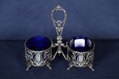 deux bols en verre bleu avec des anses en argent sur fond bleu